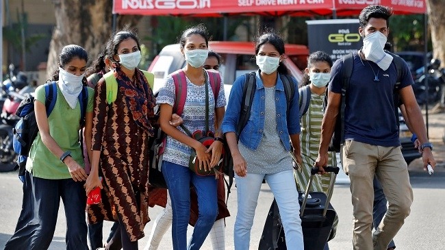 A group of students wearing protective masks walk outside a railway station amid coronavirus fears in Kochi, India. (Photo: Reuters)