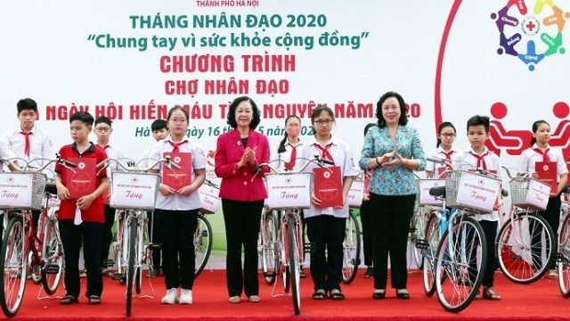 Politburo member Truong Thi Mai (centre, in red coat) and a Hanoi leader present bikes and scholarships to disadvantaged students at the event. (Photo: hanoi.gov.vn)