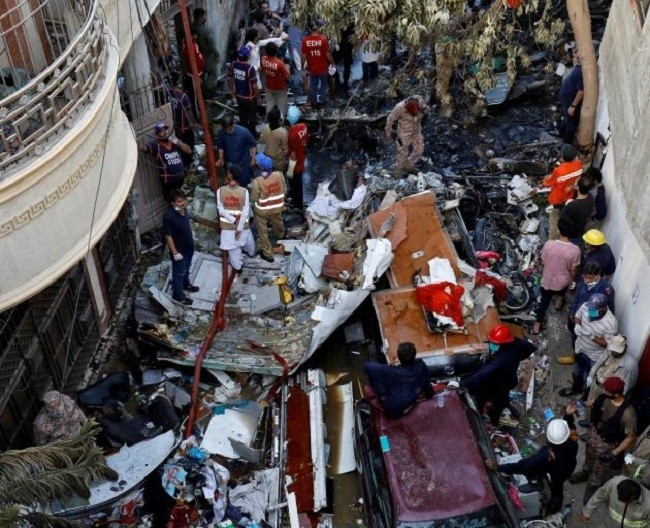 Rescue workers gather at the site of a passenger plane crash in a residential area near an airport in Karachi. (Photo: Reuters)