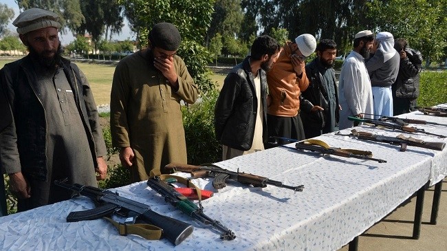 Former Afghan Taliban fighters stand next to weapons before handing them over as part of a government peace and reconciliation process at a ceremony in Jalalabad on March 1, 2020. (Photo: AFP)