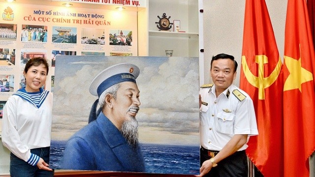 Painter Nguyen Thu Thuy (L) presents an oil portrait of Uncle Ho to a representative of the High Command of the Vietnam Navy. (Photo: phunuvietnam.vn)