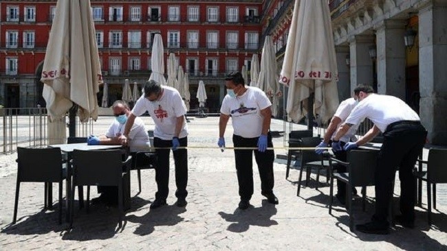Workers use measuring tape to check social distancing as they set up a terrace which will be allowed to open from May 25, at Plaza Mayor Square in Madrid, Spain, May 24, 2020. (Photo: Reuters)