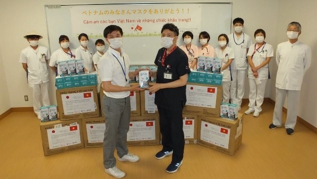 A Japanese representative (R) receives the face masks donated from CME Vietnam.
