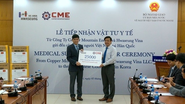 Vice Chairman of the State Committee for Overseas Vietnamese, Nguyen Hoanh Nam (left), receiving the token of 25,000 medical face masks presented by General Director of CME Energy Company Bui Trung Kien.