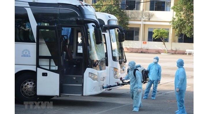 Medical workers spray disinfectant onto coaches carrying Vietnamese citizens brought home from the Republic of Korea. (Photo: VNA)