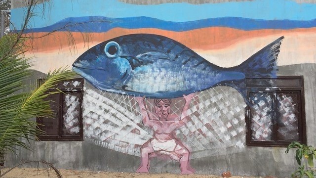 A mural painting features a man lifting a tuna by painter Nguyen Thuong Hy. 