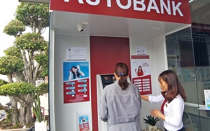 An employee of the Agribank branch in Duc Hoa district, Long An province is instructing a customer to perform steps to deposit money into an ATM.