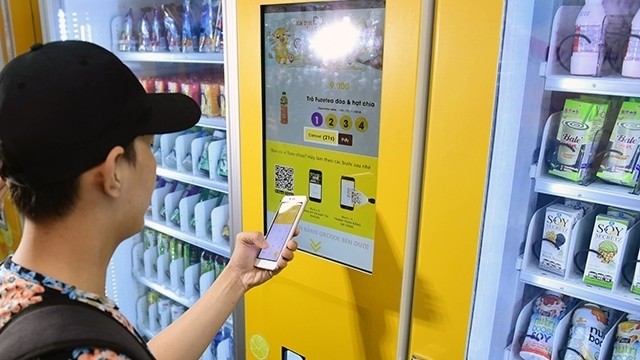A man uses his mobile phone to buy a drink at a vending machine in Ho Chi Minh City.