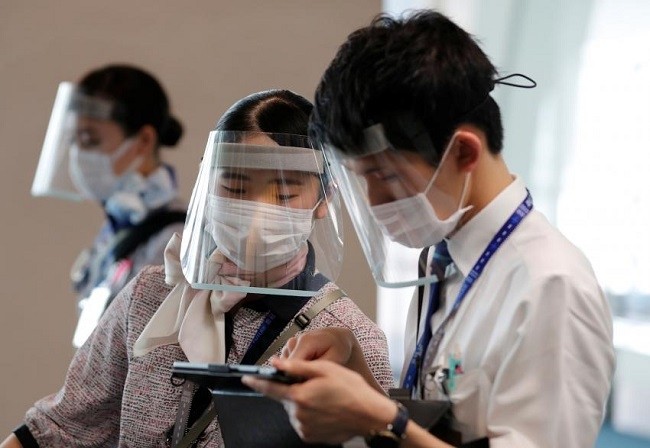 Staff members of All Nippon Airways wearing protective masks and face shields work at a boarding gate at Haneda airport in Tokyo on June 4. (Photo: Reuters)