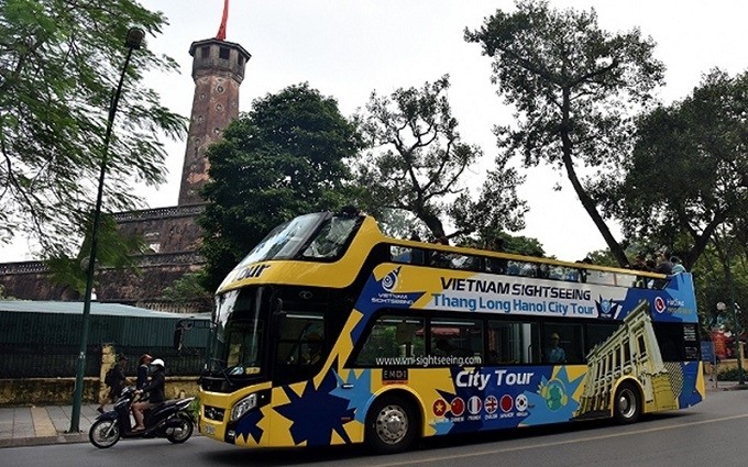 An open-top double-decker bus passes the Vietnam Military History Museum in Hanoi. (Photo: NDO/Duy Linh)