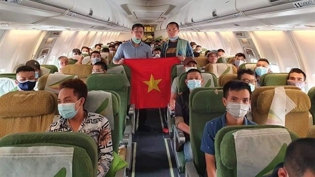 Vietnamese citizens head home onboard a flight. (Photo: VNA)