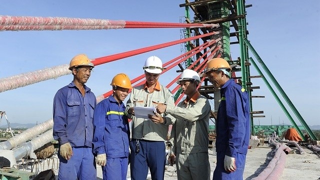 Workers and engineers at the construction site of the Cua Hoi Bridge