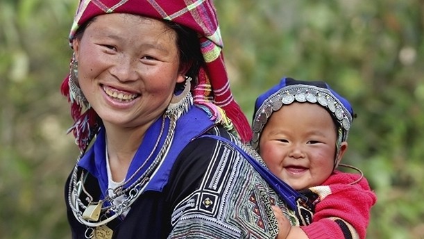 A H’mong ethnic boy smiling on the back of his mother 