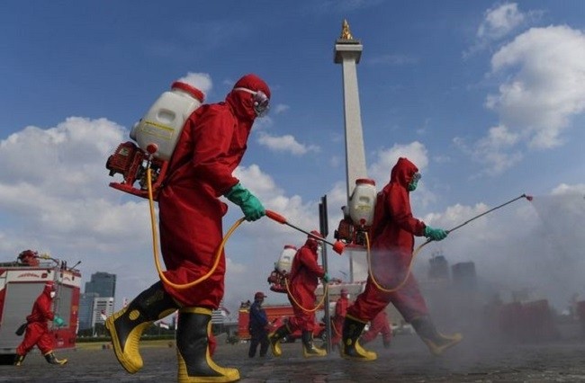 Firefighters wearing protective suits spray disinfectant at the National Monument area to prevent the spread of the coronavirus disease (COVID-19) in Jakarta, Indonesia June 17, 2020. (File photo: Antara Foto via Reuters).