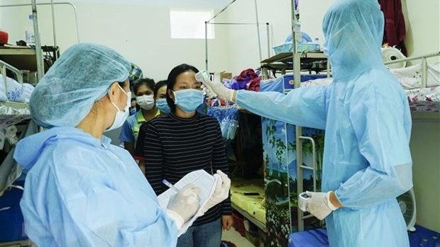Vietnamese medical workers check temperature for Lao students. (Photo: VNA)
