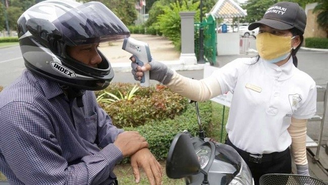 A security guard checks a man’s temperature before he enters a Phnom Penh hotel. (Source: The Phnom Penh Post/Asian News Network).  