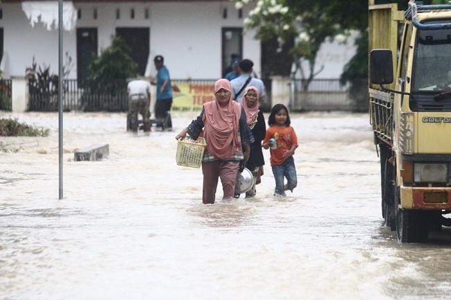 Residents wade through flood water with their belongings after flash flood hit Luwu Utara, Indonesia, July 16, 2020. (Photo: Xinhua)