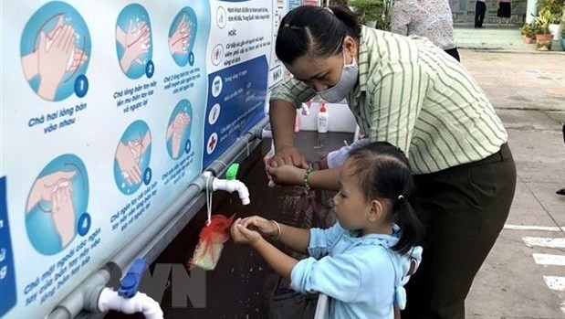 A teacher guides a student how to wash hands correctly (Photo: VNA)