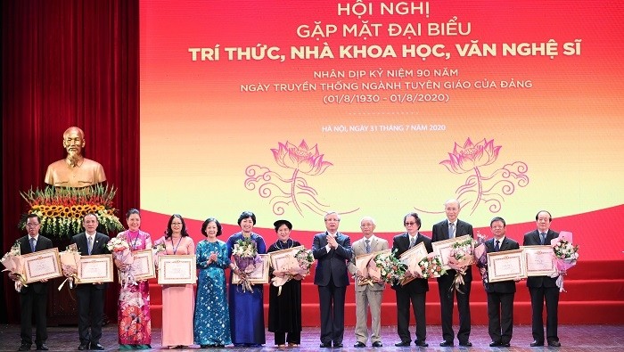 Permanent member of the Party Central Committee’s Secretariat Tran Quoc Vuong (centre, in black suit) and Head of the Party Central Committee’s Commission for Mass Mobilisation Truong Thi Mai (fifth from left) present certificates of merit from the Party Central Committee’s Commission for Communications and Education for intellectuals, scientists and artists at the meeting. (Photo: VGP)