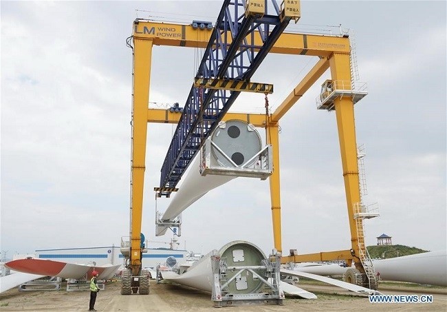 A worker operates a gantry crane to lift wind turbine blades at the Qinhuangdao economic and technological development zone in Qinhuangdao, north China's Hebei Province, Aug. 1, 2020. (Photo: Xinhua)