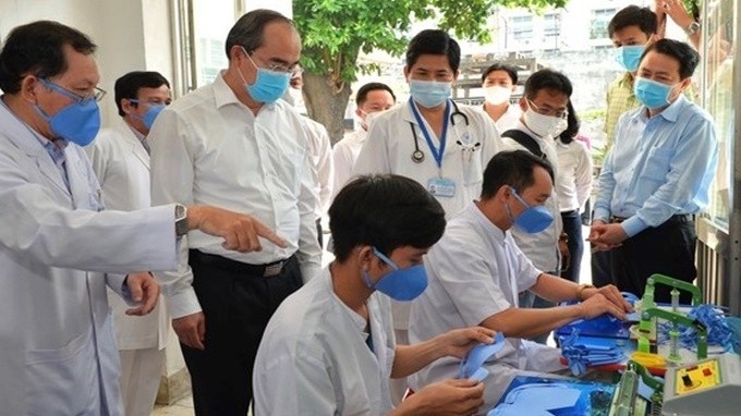 Politburo member and Secretary of the Ho Chi Minh City Party Committee Nguyen Thien Nhan (second from left) visits a face mask production site at Thong Nhat Hospital. (Photo: Sai Gon Giai Phong)