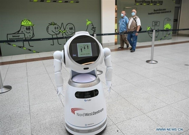 People walk past a smart robot explaining COVID-19 prevention measures at a shopping mall in Frankfurt, Germany, Sept. 12, 2020. (Photo: Xinhua)