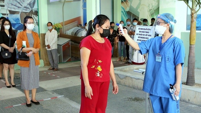 A medical staff member measures the body temperature of people before entering the examination area at Da Nang Hospital, Da Nang, September 15, 2020. (Photo: VNA)