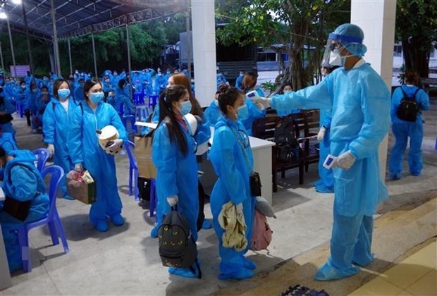Measuring body temperature of those returning home from Singapore (Photo: VNA)