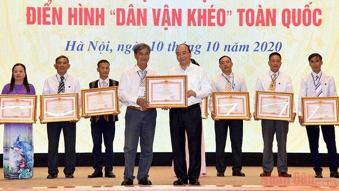 Prime Minister Nguyen Xuan Phuc (R) presents certificates of merit to exemplary models from the mass mobilisation movement at the event