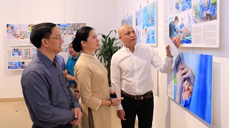 Photographer Nguyen A (R) introduces  his photos to visitors attending the opening ceremony of his exhibition ‘Vietnamese spirit in the fight against COVID-19 pandemic’ in Hanoi on September 19 (Photo: Vietnam Pictorial)