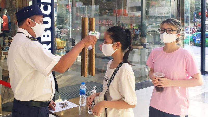 Customers have their temperatures checked before entering a shopping centre in Hanoi. (Photo: Ha Noi Moi)