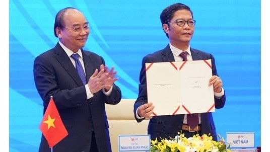 Minister of Industry and Trade Tran Tuan Anh (R) inks the pact on behalf of Vietnam. (Photo: VGP)