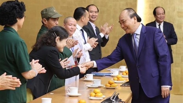 Prime Minister Nguyen Xuan Phuc shakes hands with people with major contributions to the community. (Photo: VNA)