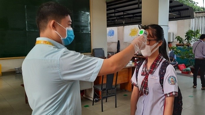 A student gets her body temperature checked before entering Thu Duc High School in Thu Duc District, Ho Chi Minh City. (Photo: NDO/Cao Tan)