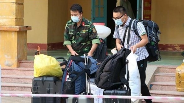 A soldier helps a citizen handle luggage at a military-managed quarantine site (Photo: VNA)