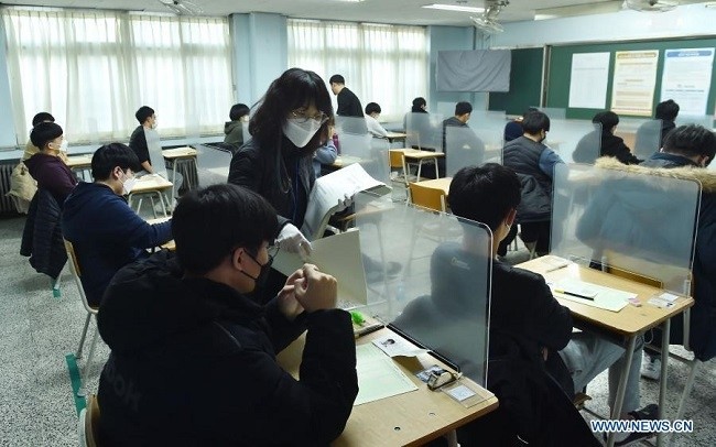 Invigilators hand out test paper to examinees attending the College Scholastic Ability Test (CSAT) in Seongnam City of Gyeonggi Province, Republic of Korea, Dec. 3, 2020. The ROK students took the annual CSAT on December 3 amid a sharp resurgence of COVID-19 infections across the country. (Photo: Xinhua)