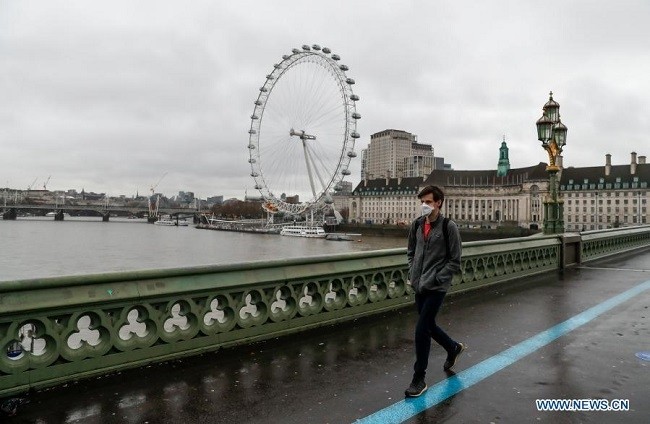 A man wearing a face mask walks past the "London Eye" by the River Thames in London, Britain, on Dec. 21, 2020. (Photo: Xinhua)