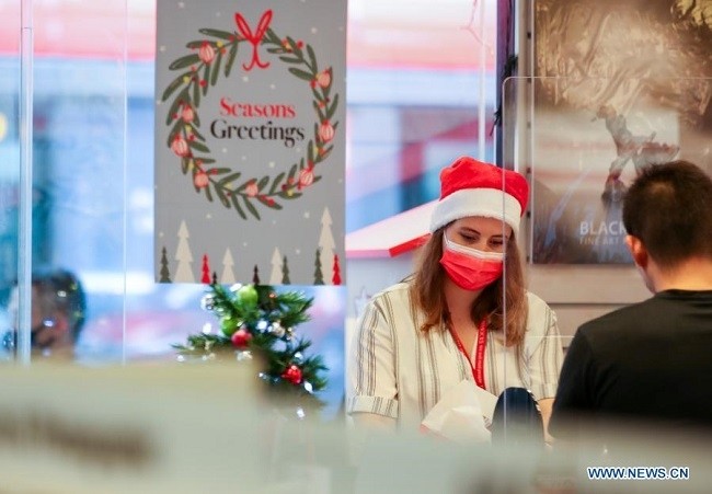 A woman wearing a Christmas hat and a face mask works in a shop in Sydney, Australia, Dec. 22, 2020. Officials in the Australian state of New South Wales (NSW) have named over 100 venues across Sydney as potential COVID-19 hotspots, instructing anyone who attended them to self-isolate and get tested. NSW recorded eight locally acquired cases of COVID-19 on Tuesday, taking a recent outbreak to 90 infections. (Photo: Xinhua)