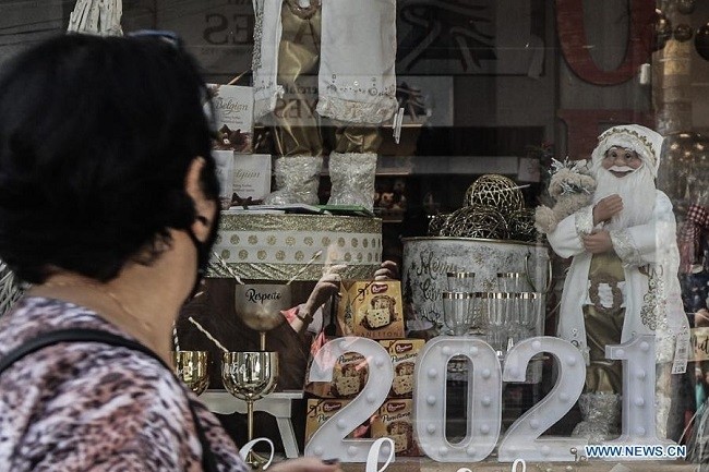 A woman walks past a shop window decorated with a "2021" light fixture in Sao Paulo, Brazil, Dec. 28, 2020. Brazil registered 20,548 new COVID-19 cases in the past day, taking the national count to 7,504,833, the country's health ministry said Monday. The nationwide COVID-19 death toll rose to 191,570 after 431 more deaths were reported in the last 24 hours, said the ministry. (Photo: Xinhua)