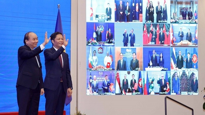 Vietnamese Prime Minister Nguyen Xuan Phuc (L) and Minister of Industry and Trade Tran Tuan Anh, together with leaders of other RCEP member countries, witness the pact signing via videoconference on November 15, 2020. (Photo: VNA)
