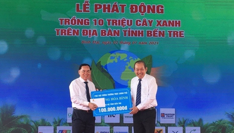 Deputy Prime Minister Truong Hoa Binh (R) presents VND100 million to Ben Tre.