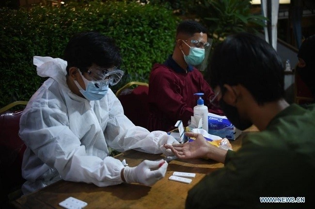 A health worker takes blood samples from a man who violated the COVID-19 health protocol in Jakarta, Indonesia on Dec. 26, 2020. (Photo: Xinhua)