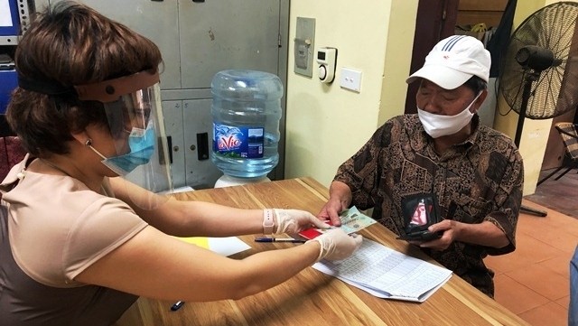 A local in O Cho Dua ward in Hanoi’s Dong Da district receives financial support from the State to ease difficulties caused by COVID-19. (Photo: NDO/Duy Linh)