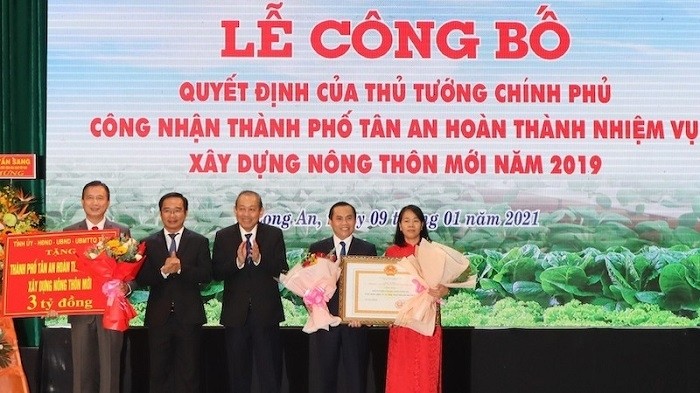 Deputy Prime Minister Truong Hoa Binh (C) hands over the Prime Minister's decision recognising Tan An city as completing its new rural area construction process to leaders of Tan An city. (Photo: NDO/Thanh Phong)