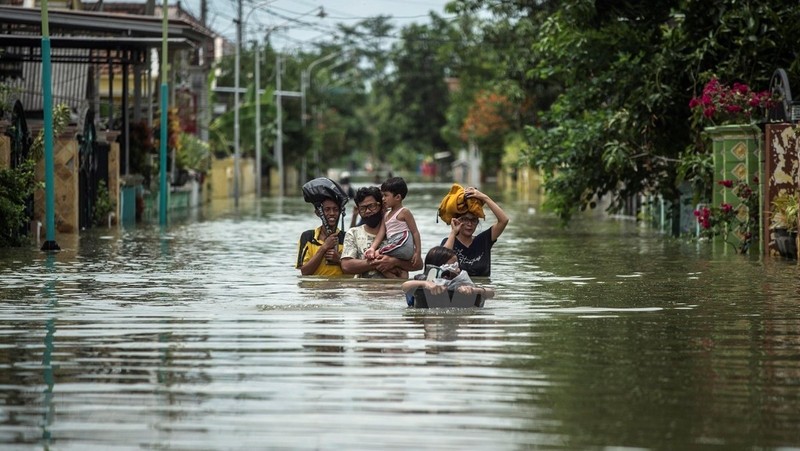 Residents evacuate their flooded homes in Gresik, East Java, Indonesia on December 15, 2020, as the rainy season brings floods to many areas in Jakarta and Java. (Photo: AFP/VNA)