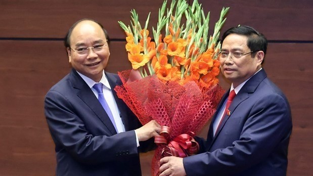Prime Minister Pham Minh Chinh presents flowers to President Nguyen Xuan Phuc, who was Prime Minister in the 2016-2021 term. (Photo: VNA)