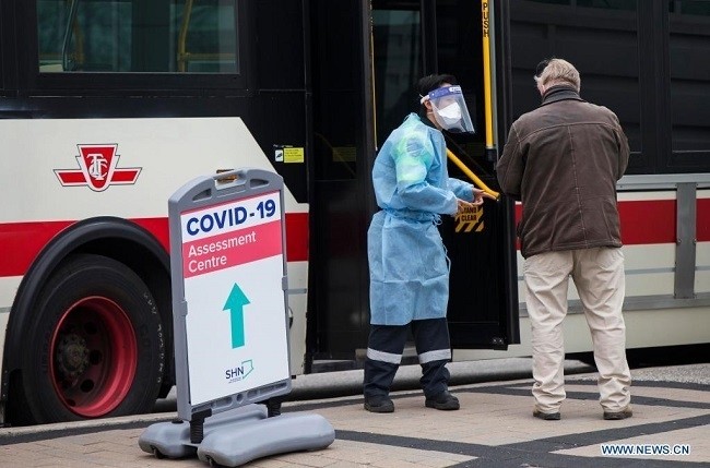 A medical worker talks to a man outside a COVID-19 testing bus in Toronto, Ontario, Canada, on April 13, 2021. Over the past week, there has been an increase of 33 percent in daily case counts with an average of almost 8,100 new cases reported per day, according to the Public Health Agency of Canada on Tuesday. (Photo: Xinhua)