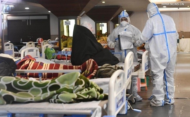 Health workers wearing protective suits treat a COVID-19 patient inside an isolation ward in Shehnai Banquet Hall near government-run Lok Nayak Jai Prakash Narayan (LNJP) hospital, in New Delhi, India, on April 13, 2021. (Photo: Xinhua)