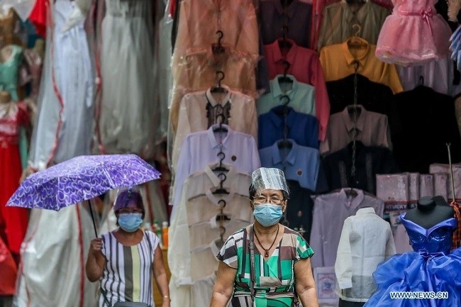 People wearing protective gear walk past a market in Manila, the Philippines, on April 15, 2021. The Philippines' Department of Health (DOH) reported on Thursday 11,429 new COVID-19 infections, bringing the total number of confirmed cases in the Southeast Asian country to 904,285. (Photo: Xinhua)