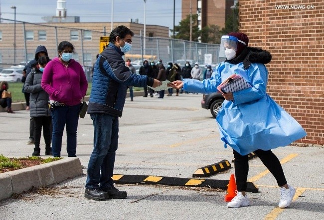A medical worker hands out a registration form to a man outside a COVID-19 vaccination clinic in Toronto, Canada, on April 22, 2021. As of Thursday afternoon, Canada's COVID-19 cases surpassed 1,150,000, hitting 1,152,717, including 23,811 deaths and 1,044,255 recoveries. (Photo: Xinhua)